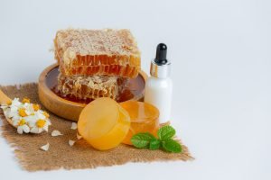 Natural skin care soap and serum with honey and honeycomb laid on white background.